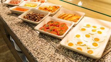 A buffet with various food options including eggs, tomatoes, and beans.