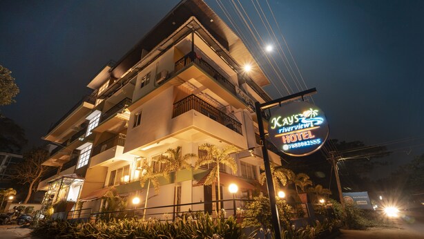 A multi-story hotel with balconies, a well-lit entrance, and a signboard. - Kay's Riverview Resort (Arpora)