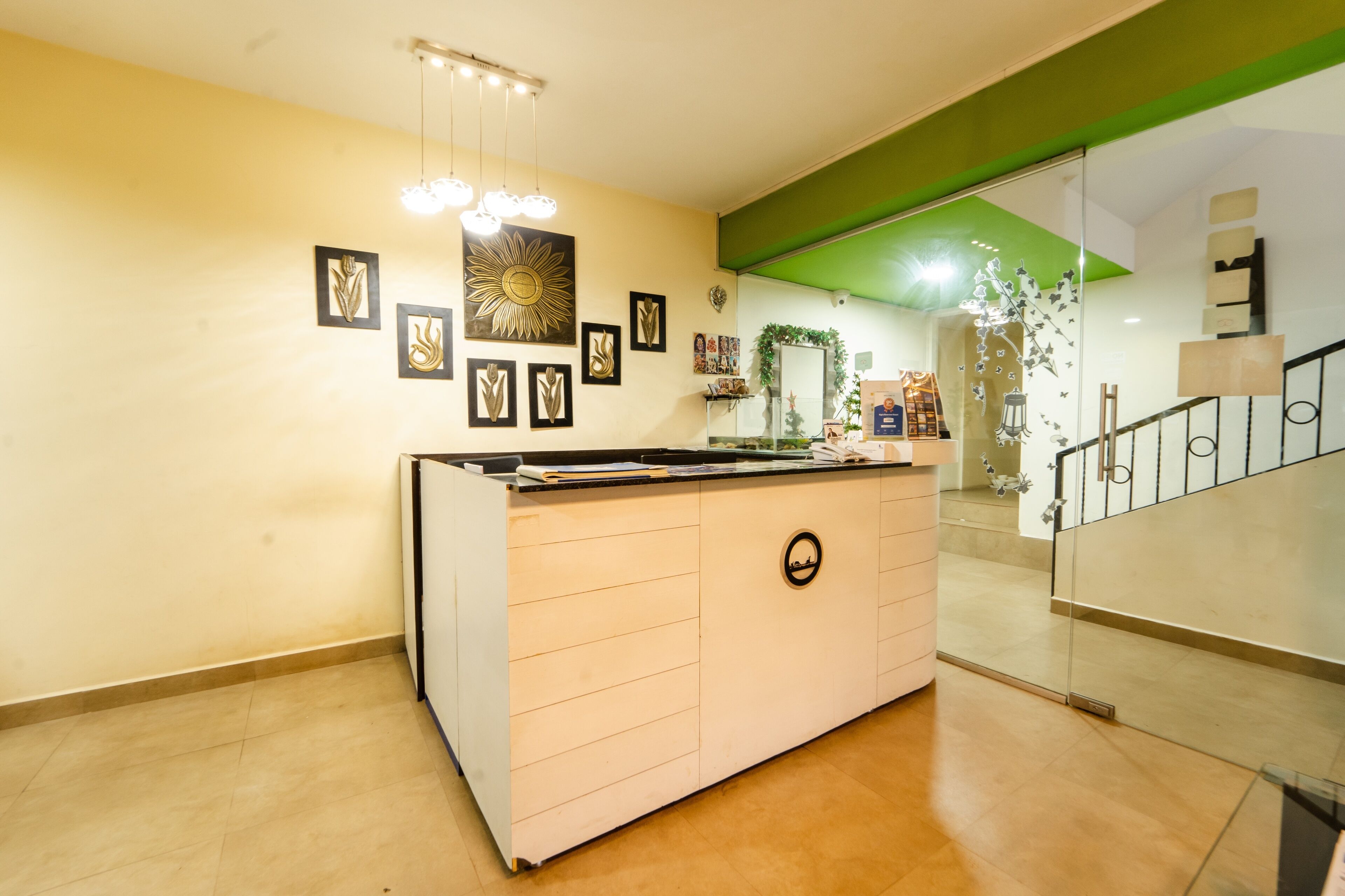 A reception area with a counter, framed artwork on the wall, and a staircase with a green accent.