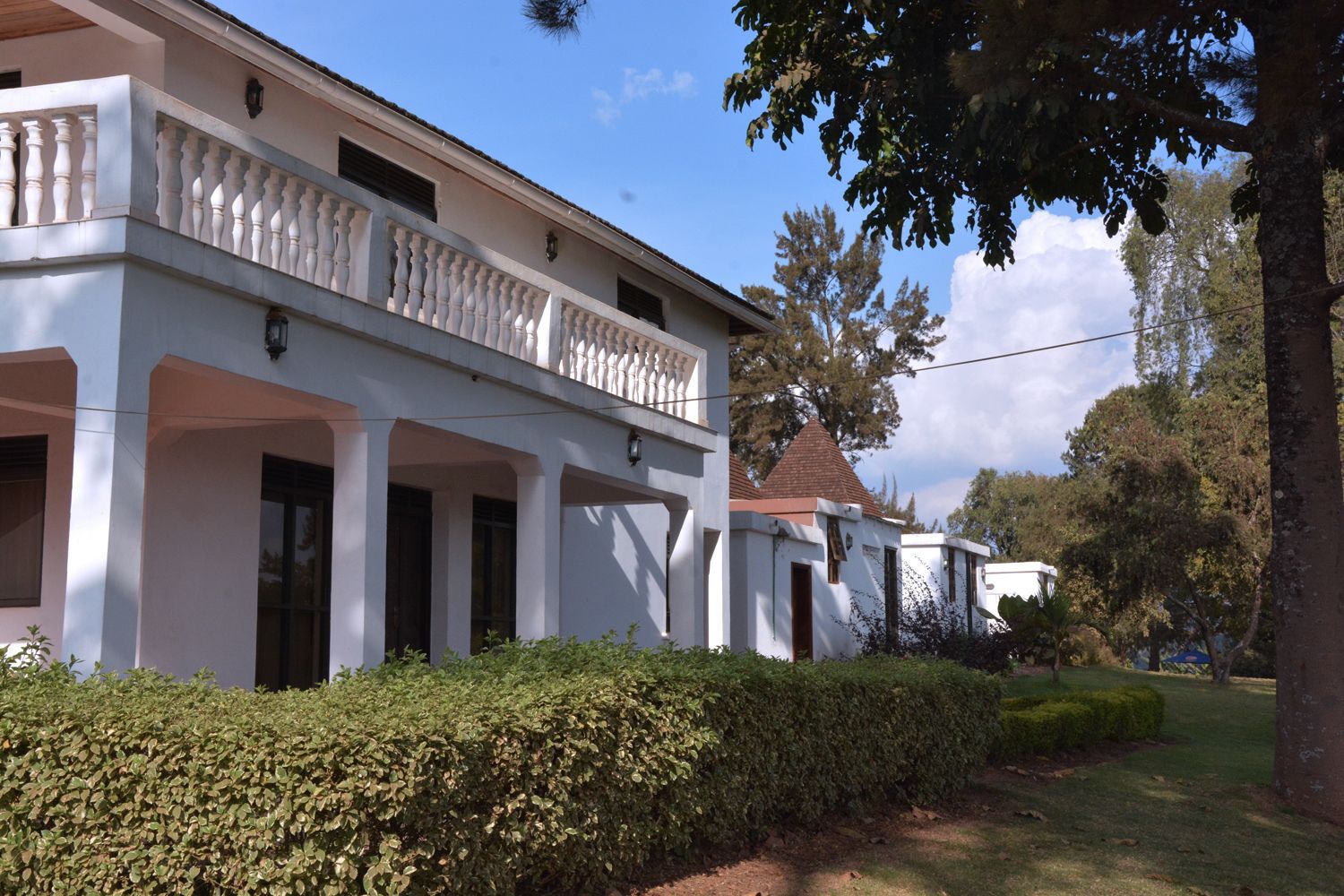 A white building with a balcony, columns, and a tiled roof.