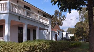 A white building with a balcony, columns, and a tiled roof.