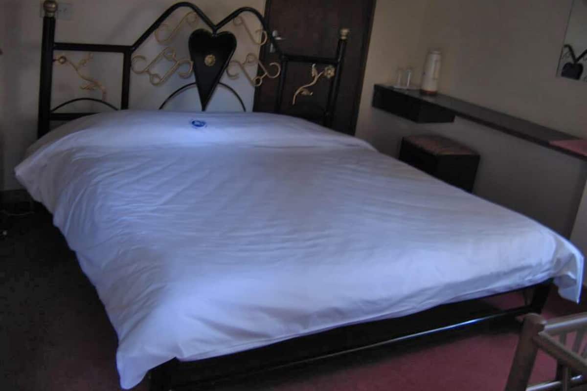 A bed with a heart-shaped headboard, a bedside table, and a nightstand.