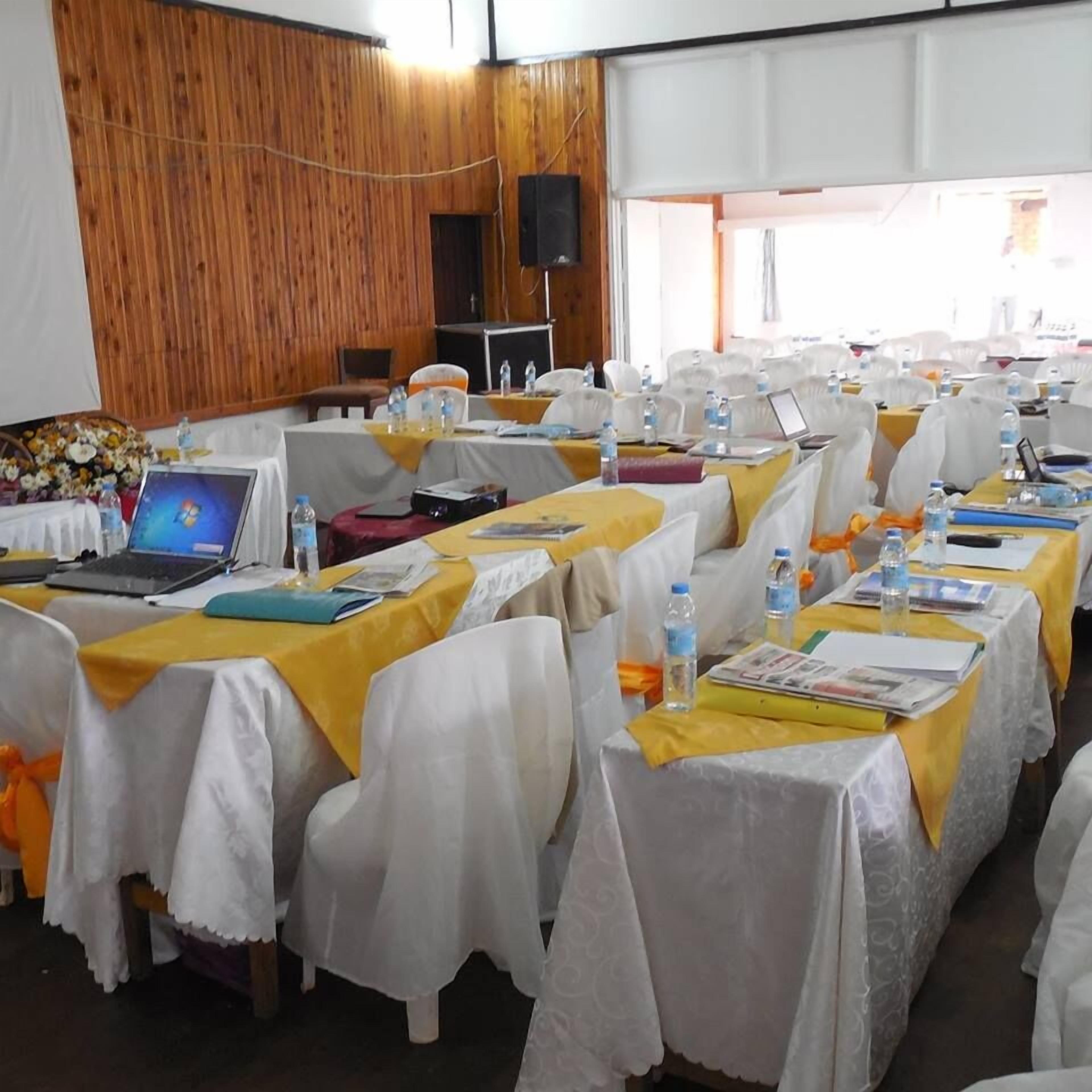 Un salón de conferencias con filas de mesas, cada una cubierta con un mantel amarillo y fundas blancas para las sillas.