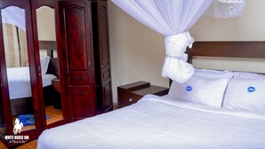 Un dormitorio con un armario de madera, una cama con ropa de cama blanca y un dosel con encaje.