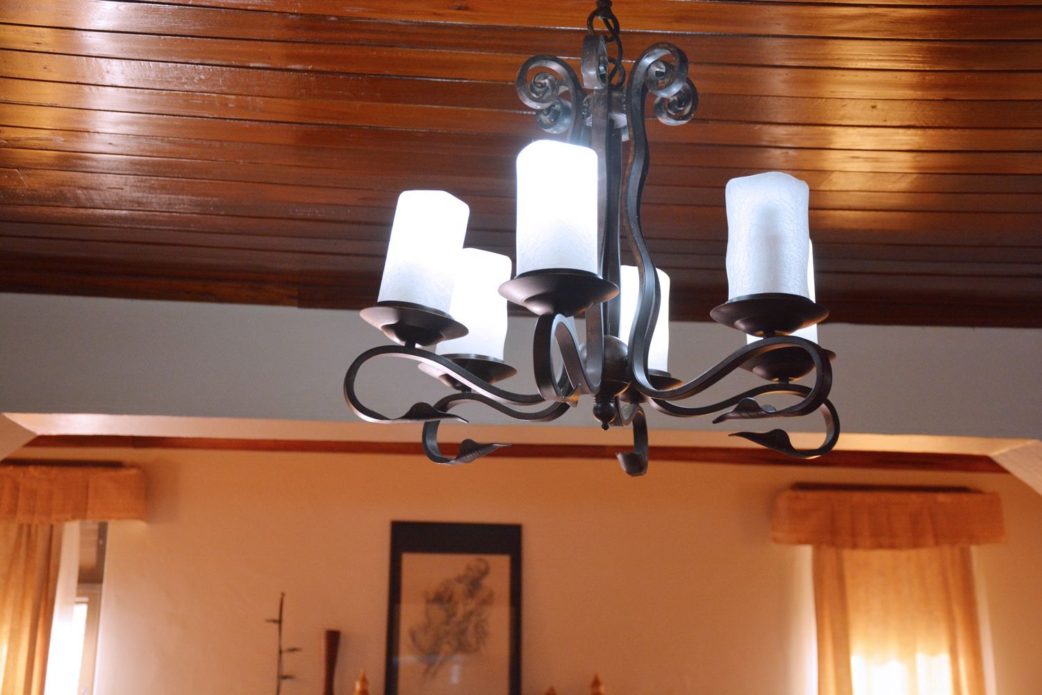 Un candelabro con cuatro luces blancas similares a velas y techo de madera.