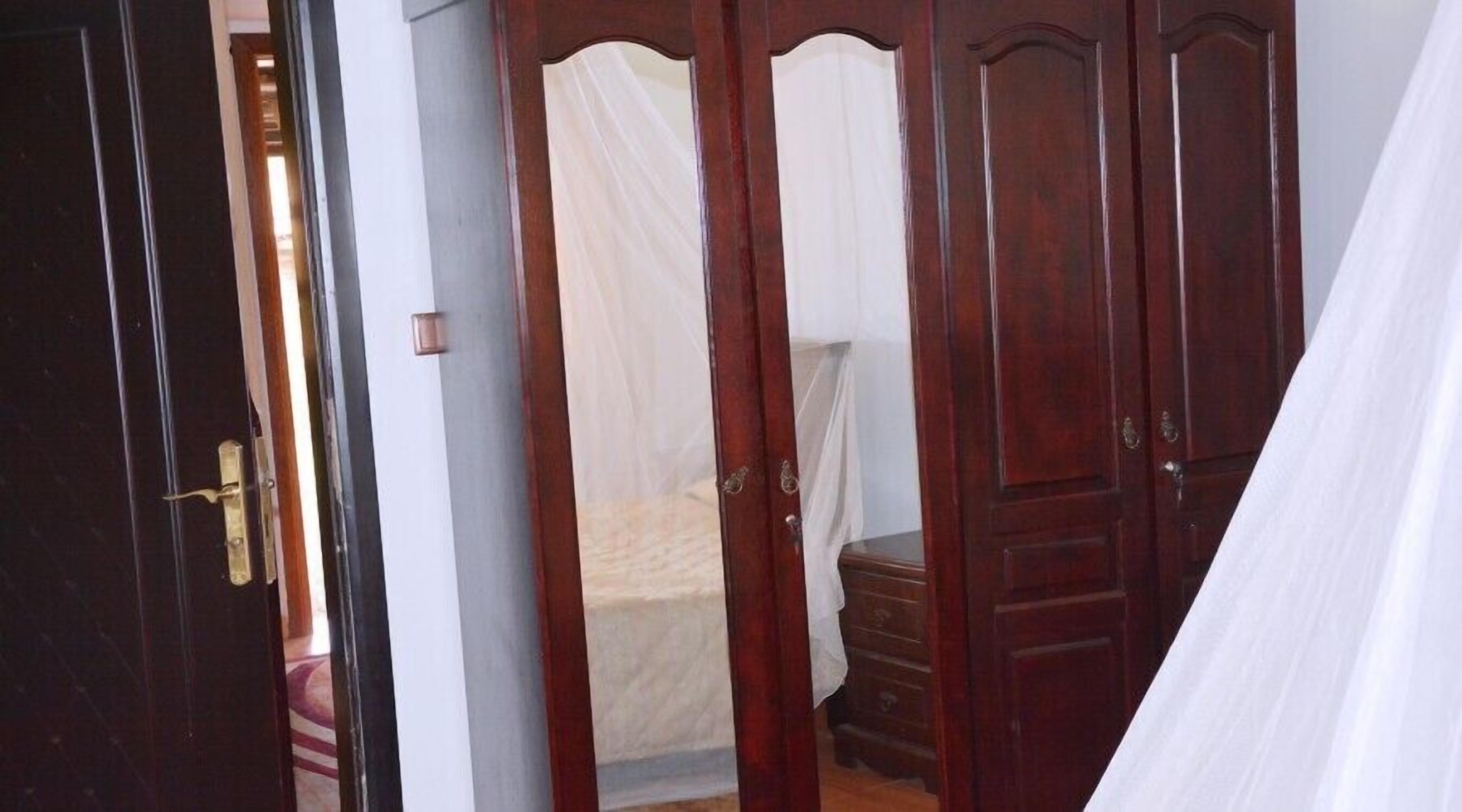 A bedroom with a bed, a nightstand, and a wooden wardrobe.