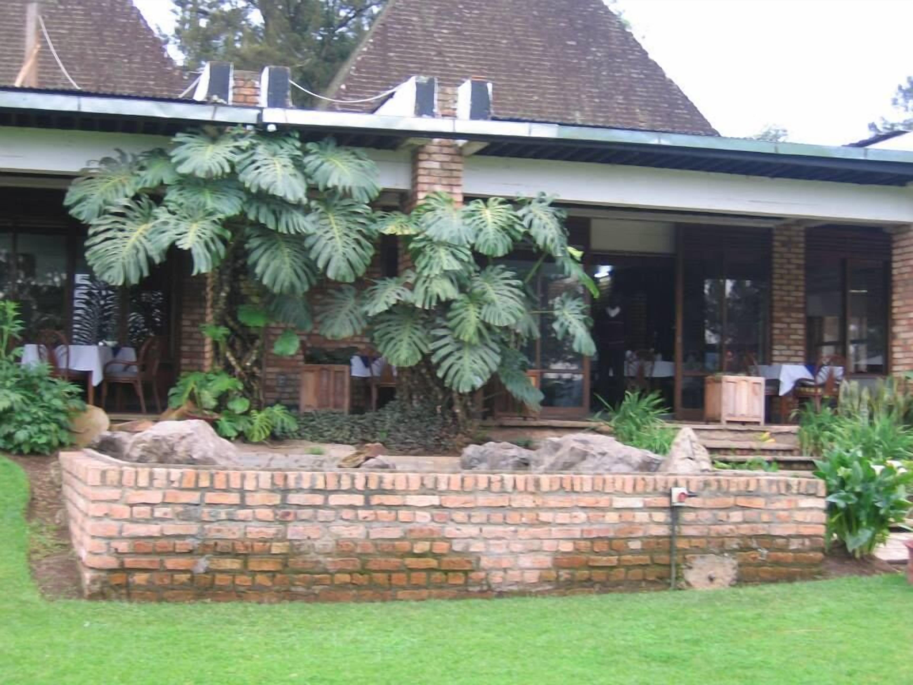 A building with a brick facade, large windows, and a garden area with tropical plants.