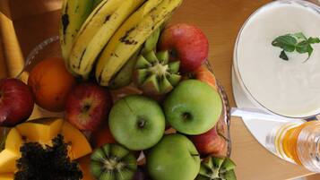 A fruit bowl with bananas, apples, and kiwi on a wooden table.