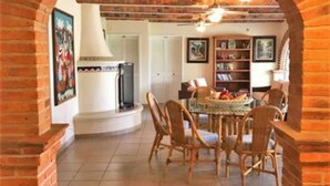 Un'area pranzo con un arco in mattoni, sedie di legno, un tavolo rotondo e una libreria sullo sfondo.