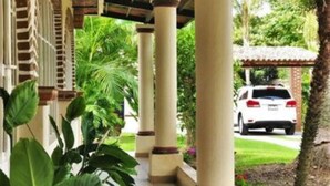 Un porticato sorretto da colonne, immerso nel verde e con un'auto parcheggiata sullo sfondo.
