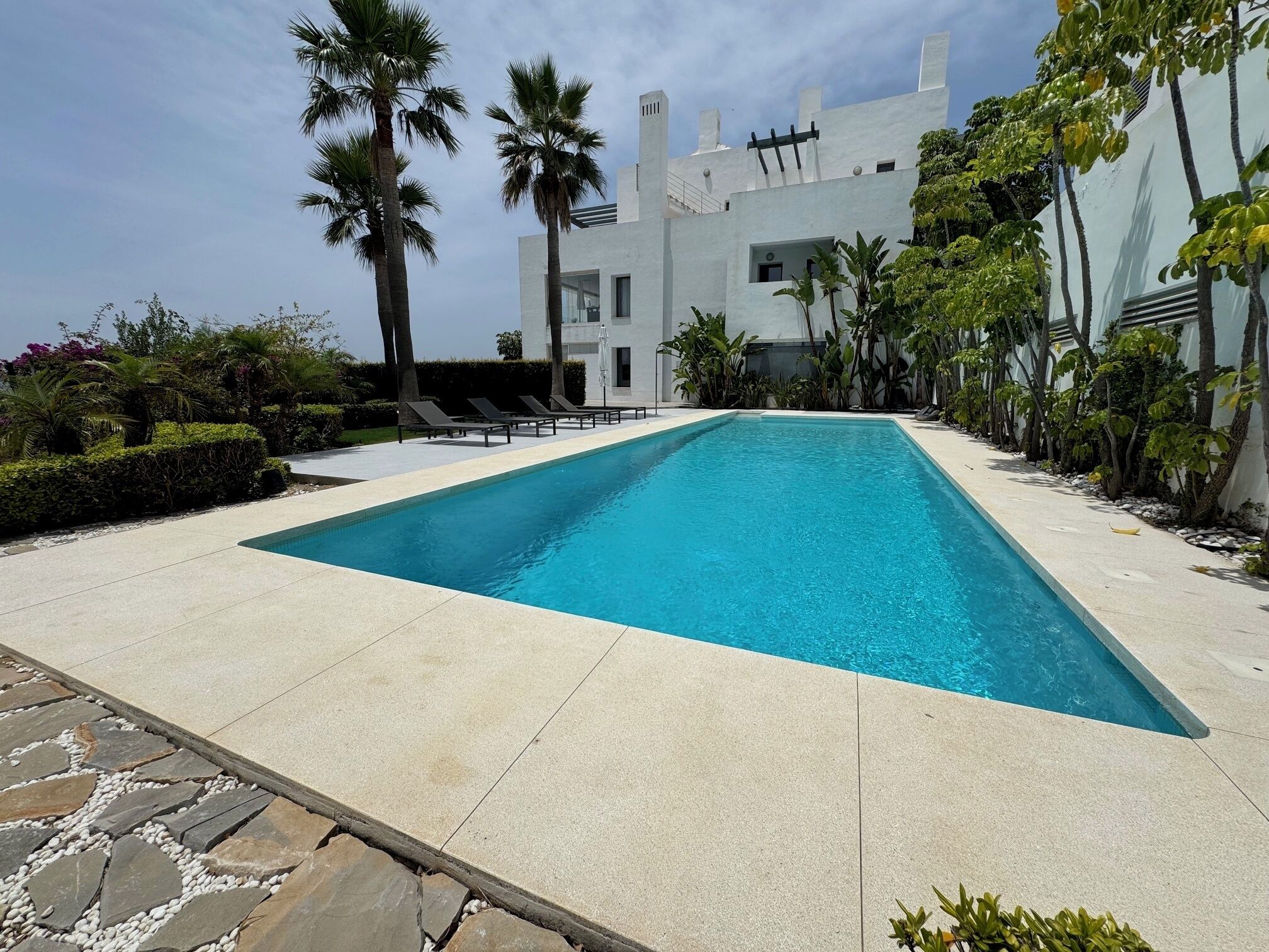 Una piscina al aire libre, sombrillas, tumbonas