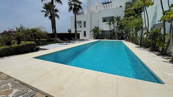 Una piscina al aire libre, sombrillas, tumbonas