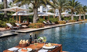 Una piscina al aire libre, sombrillas, sillones reclinables de piscina