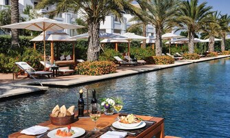 Una piscina al aire libre, sombrillas, sillones reclinables de piscina