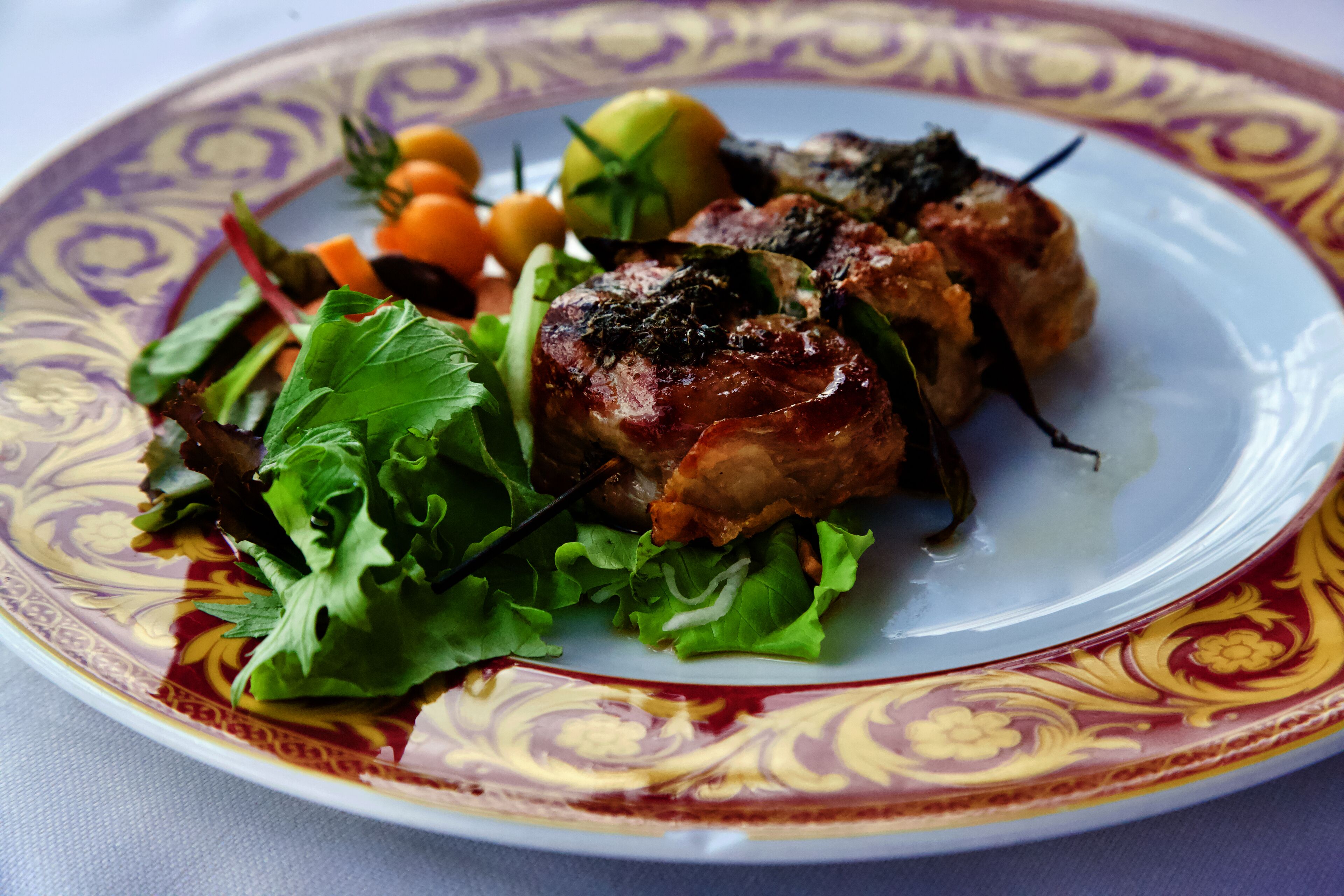 A plate with grilled meat, vegetables, and a decorative plate.