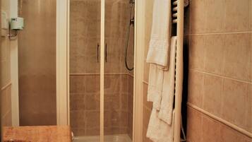 Un baño con ducha de vidrio, lavamanos y un perchero para toallas.