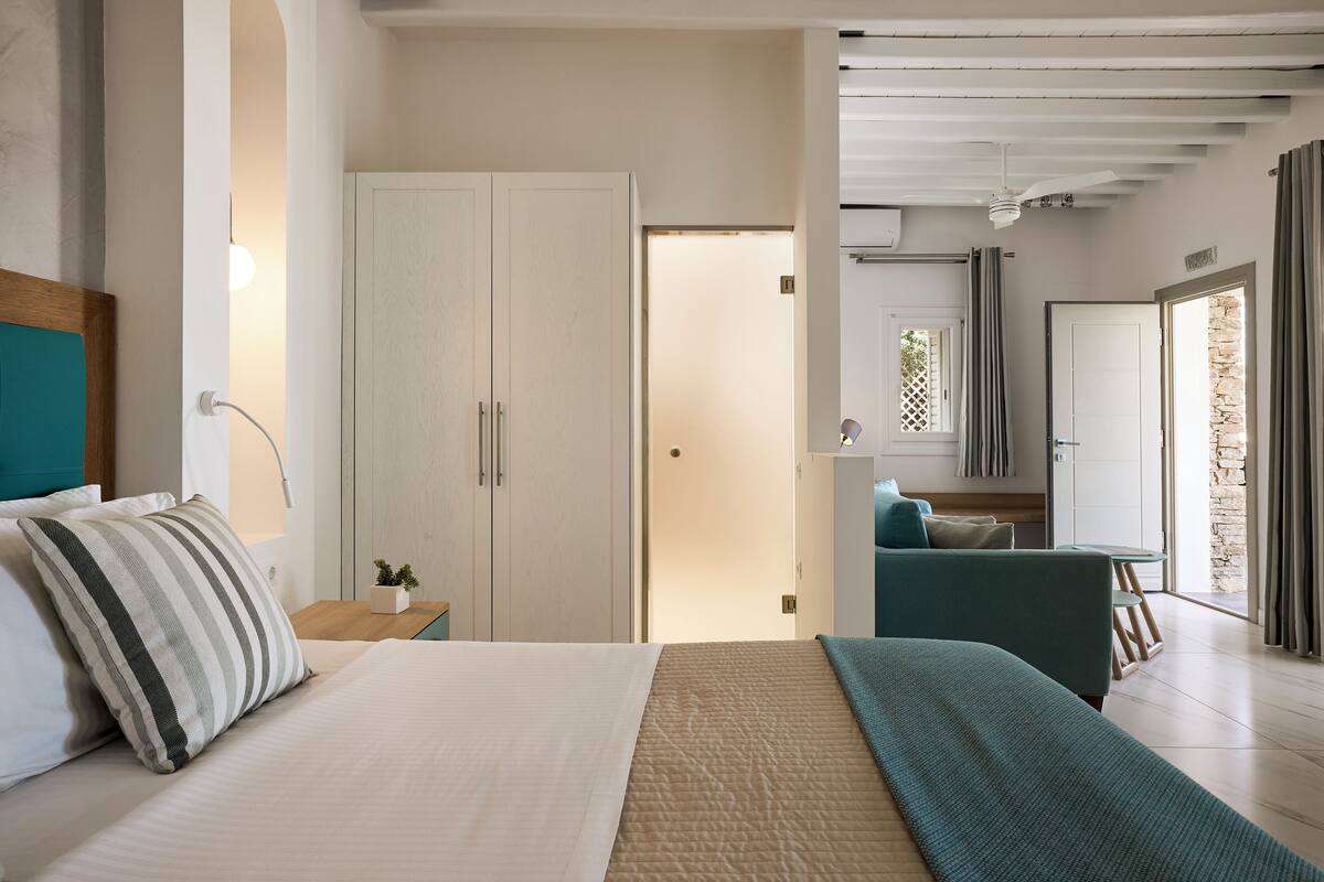 A bedroom with a bed, a wardrobe, a nightstand, a bedside table, and a view of a balcony.
