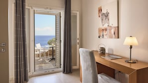 A room with a desk, chair, and a view of the sea through an open door. - Selana Suites (Sifnos)