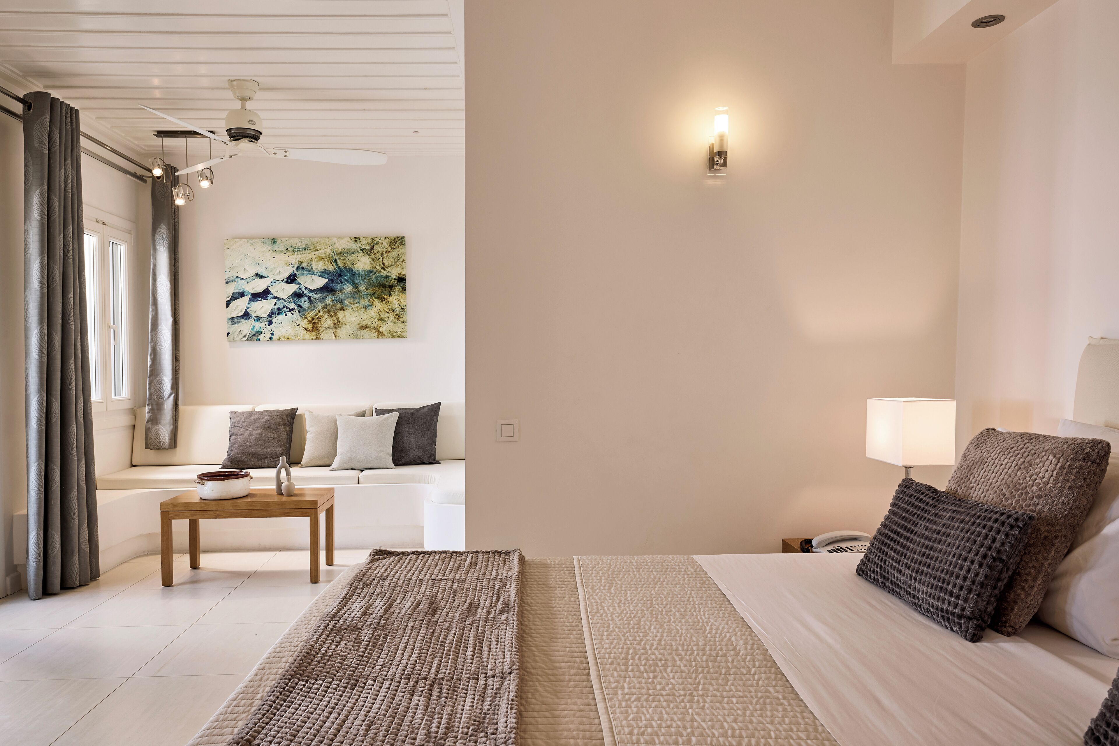 Ein modernes Hotelzimmer mit Bett, Nachttisch, Lampe und einem Kunstwerk an der Wand.