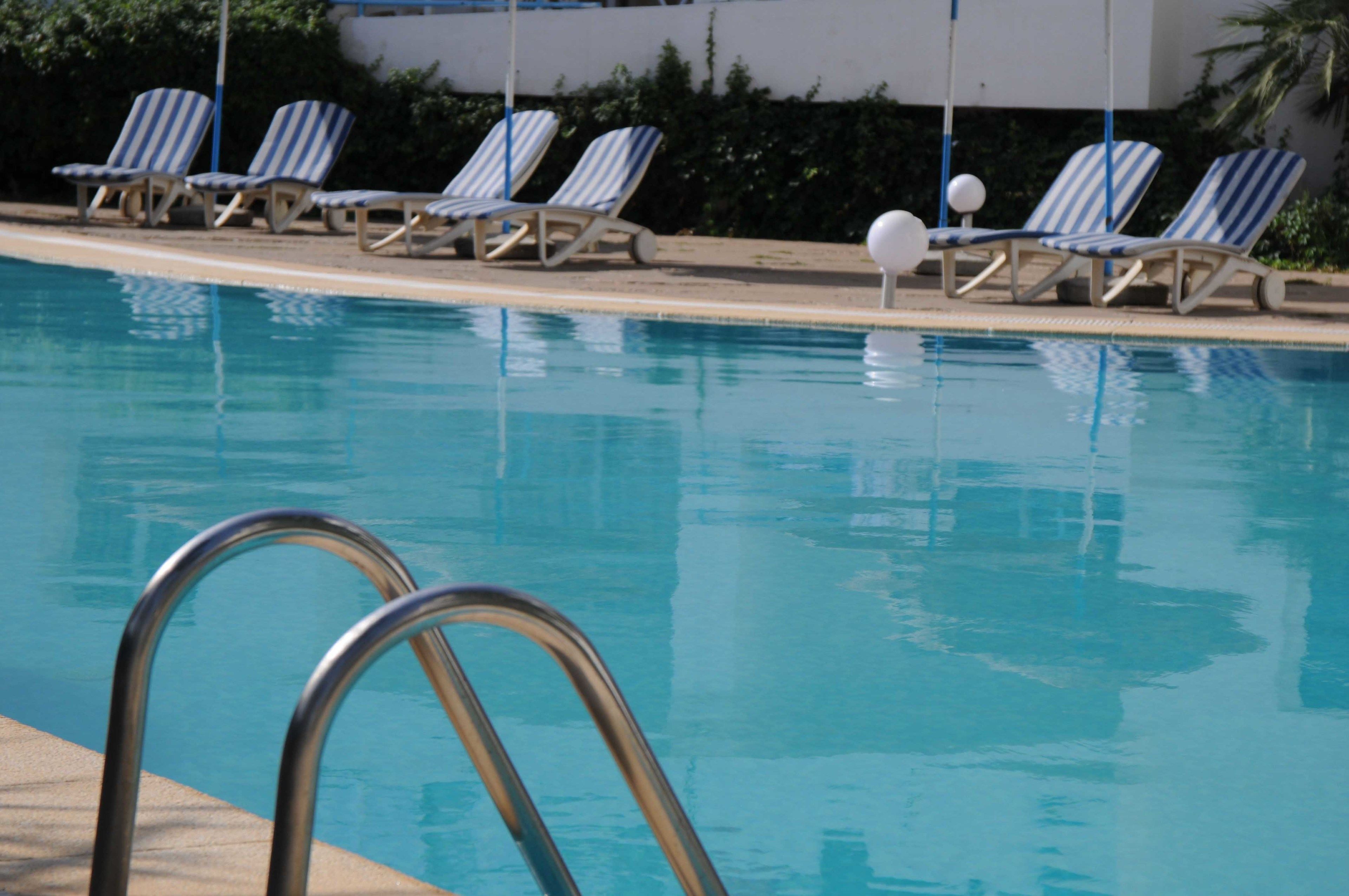 Ein Schwimmbecken mit Liegestühlen und einer Poolleiter.