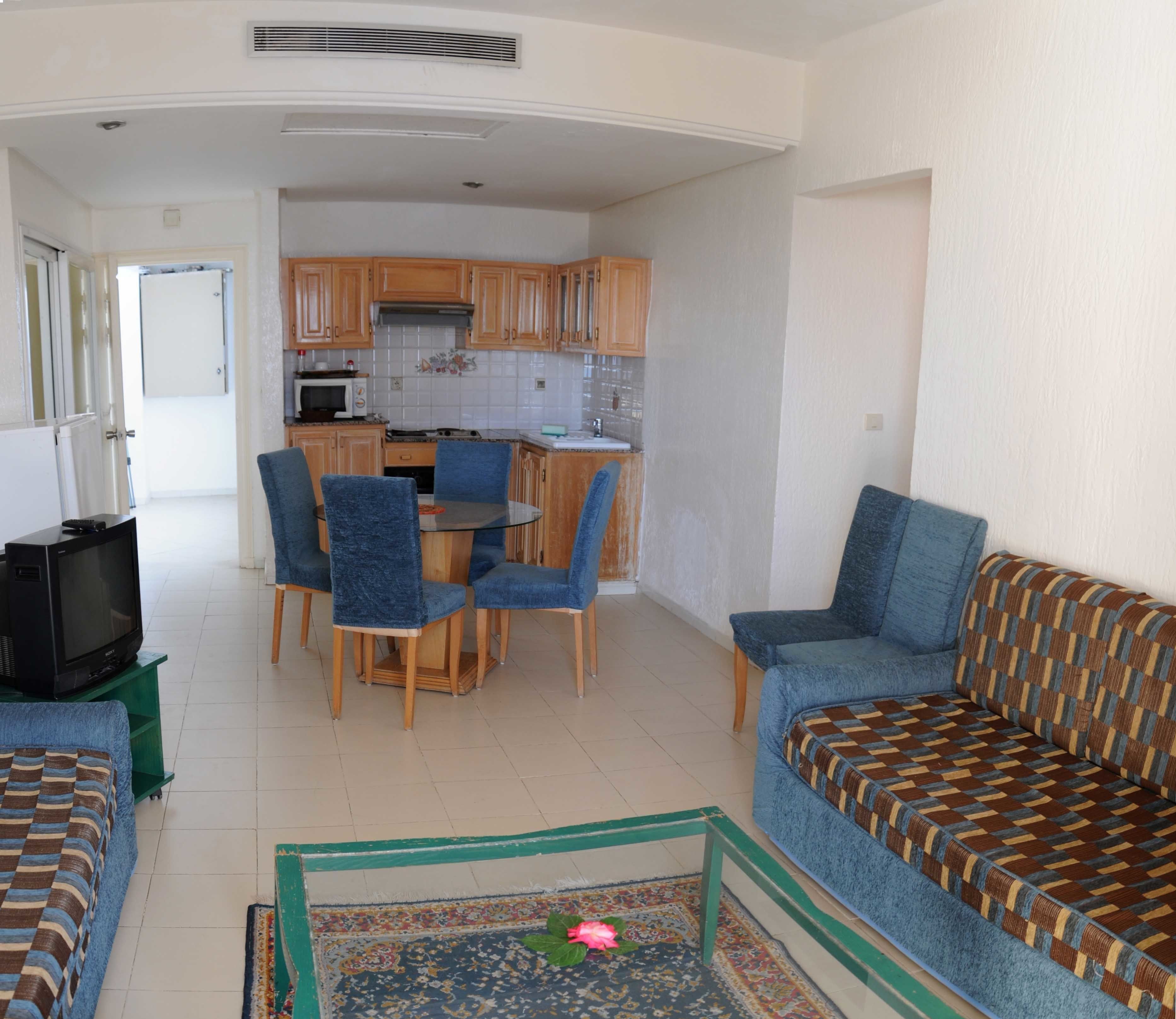 Un espacio habitable compacto con kitchenette, comedor y sofá.