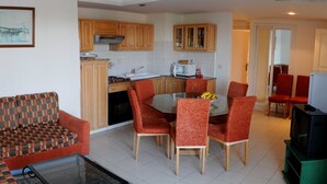 A living room with a sofa, a glass coffee table, and a dining area with a table and chairs. - Residence Corail Royal Plage (Tabarka)