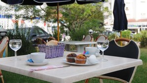 An outdoor dining table with a white tablecloth, two chairs, a basket of bread, a plate with muffins, a cup, and a glass of water. - Residence Corail Royal Plage (Tabarka)