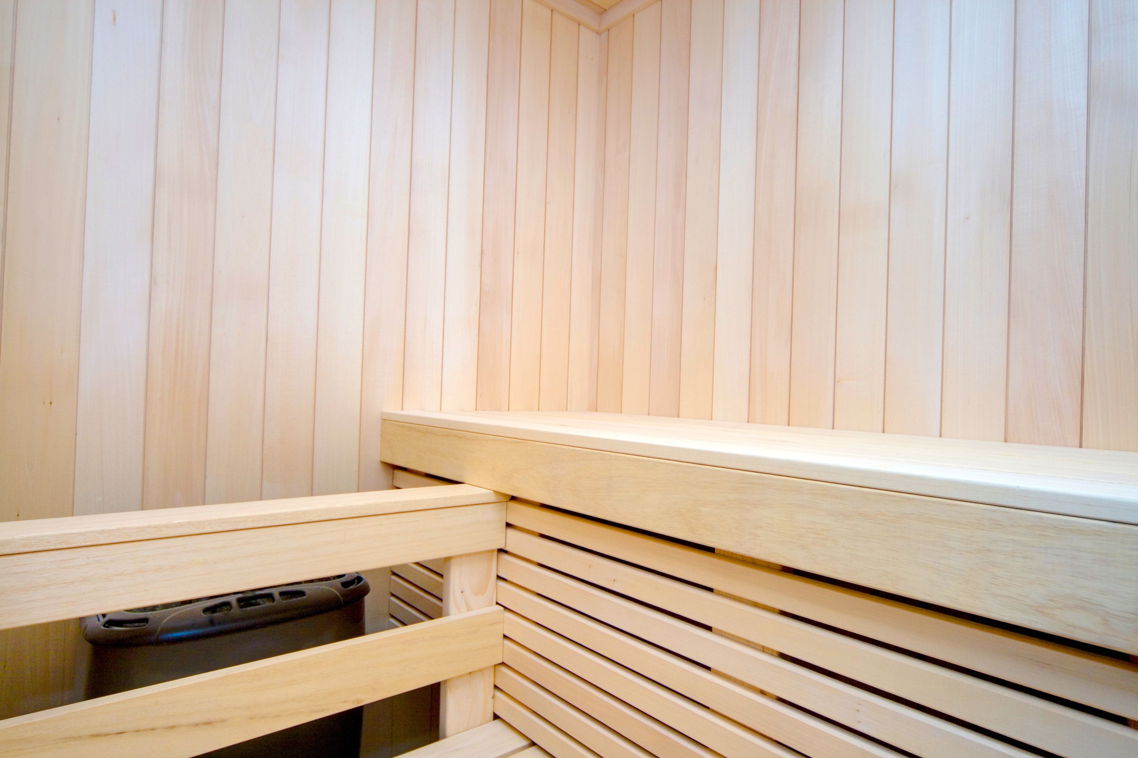 A wooden sauna with a bench and a small trash bin.