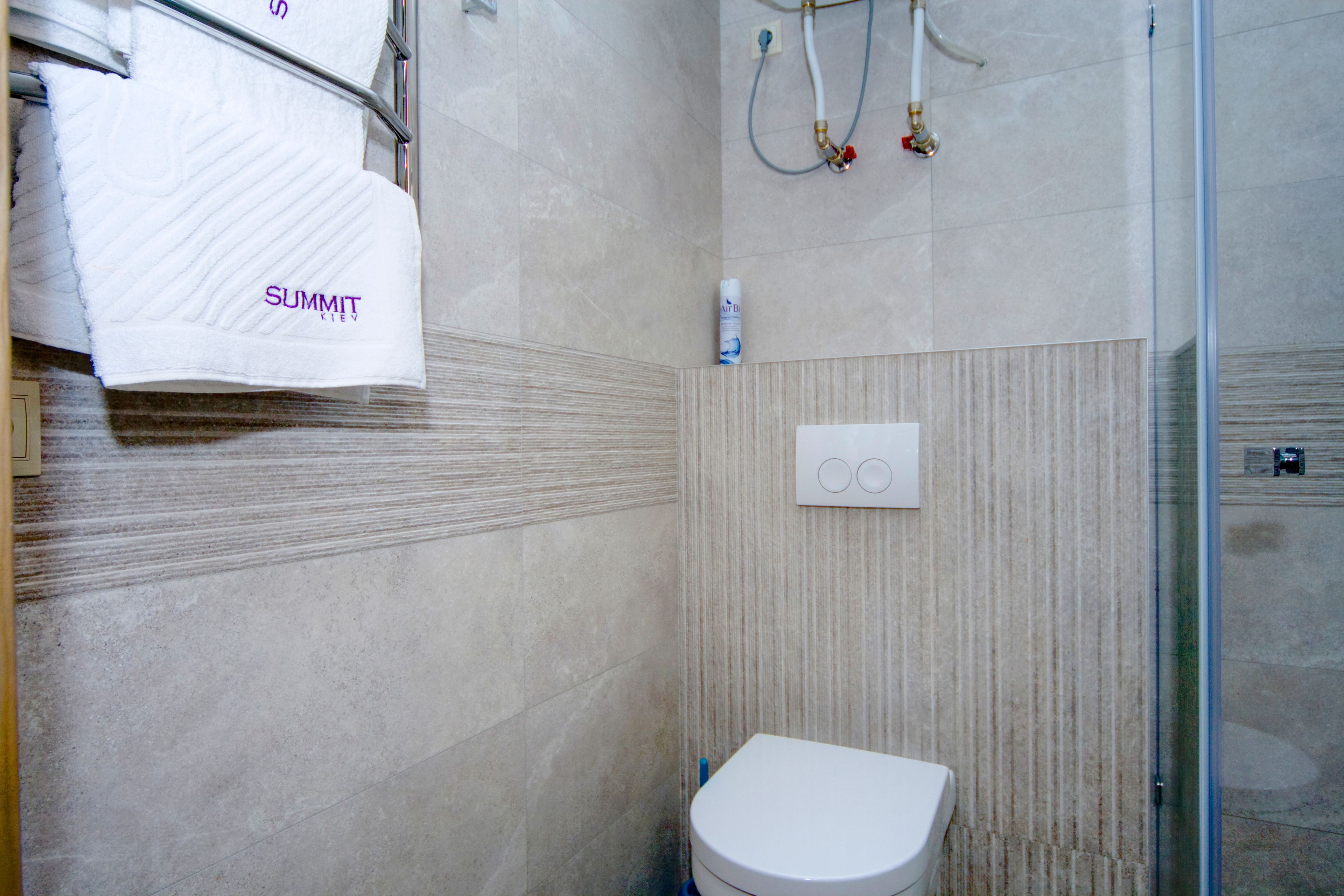 A bathroom with a white toilet, a towel rack with a white towel, and a shower area with a glass door.