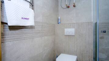 A bathroom with a white toilet, a towel rack with a white towel, and a shower area with a glass door.