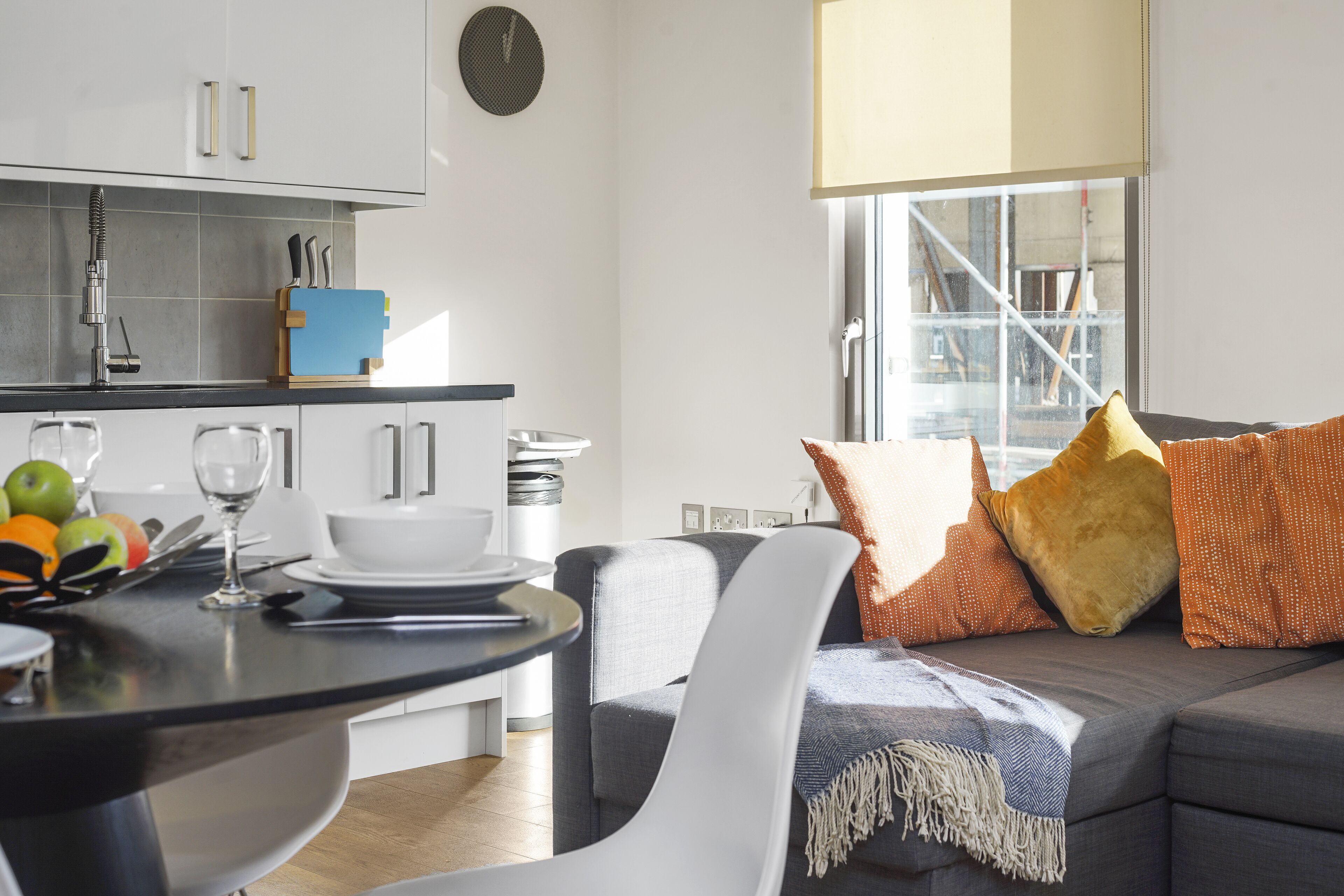 Une cuisine moderne avec des meubles blancs, un plan de travail noir et un coin repas comprenant une chaise et une table blanches.