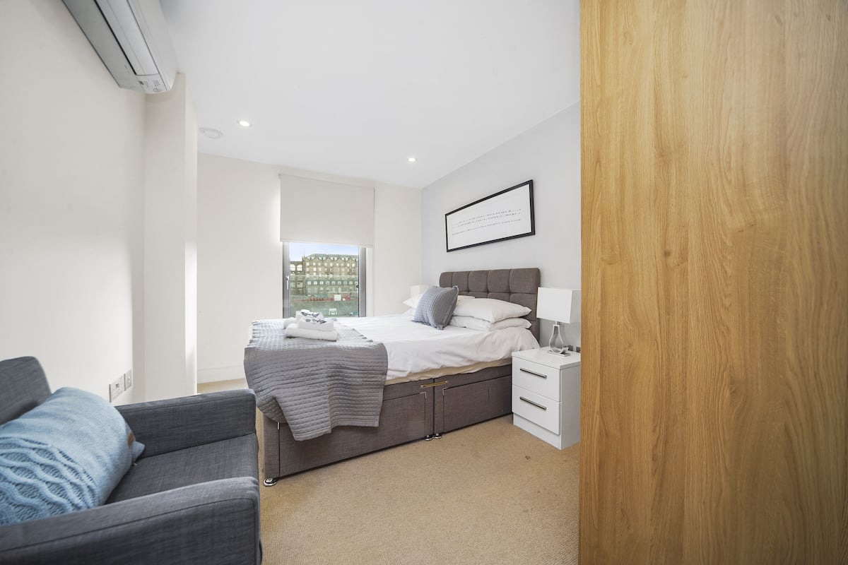 A modern bedroom with a bed, bedside table, and a view of the outside.