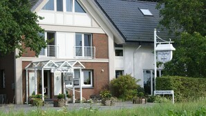 Ein zweistöckiges Gebäude mit Glastür, einer Beschilderung für 'GASTHOF Zum Jagdpark' und einem Schild für 'Biergarten'.