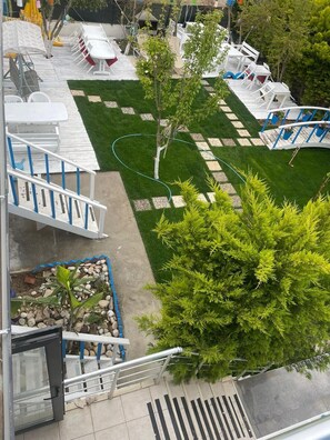 A rooftop terrace with outdoor seating, a small garden area, and a view of the surrounding buildings. - Hotel Antonio (Cesme)