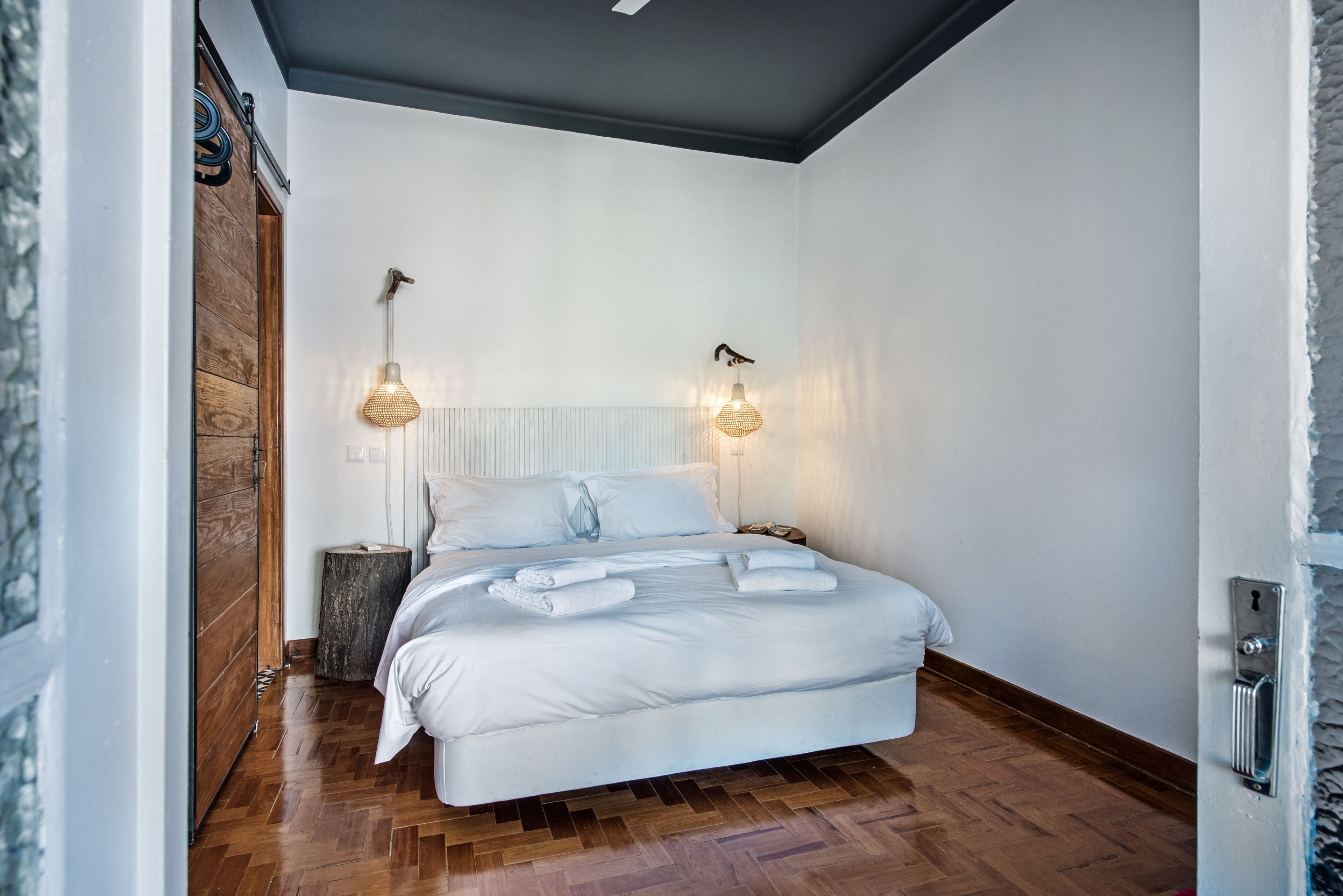 Een slaapkamer met een groot bed, twee bedlampen, een houten vloer en een wit hoofdeinde.