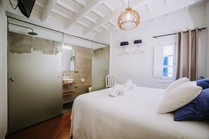 A hotel room with a bed, a bathroom, and a glass door leading to a shower area. - Petit Hotel 5 Fars - Adults Only (Ciutadella de Menorca)
