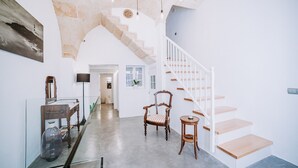A spacious interior with a staircase, a wooden chair, a small table, and a glass cabinet.