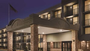 A multi-story hotel with a covered entrance, stone pillars, and a flag on top.