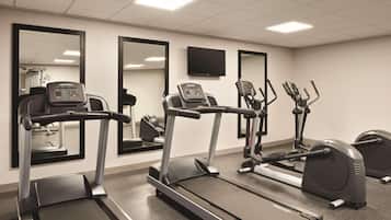 Un gimnasio con cintas de correr, elípticas y bicicletas estáticas.