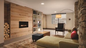 A cozy living room with a fireplace, wooden panel walls, a sofa, a coffee table, and a lamp.