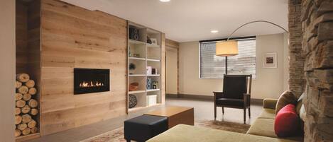 A cozy living room with a fireplace, wooden panel walls, a sofa, a coffee table, and a lamp.
