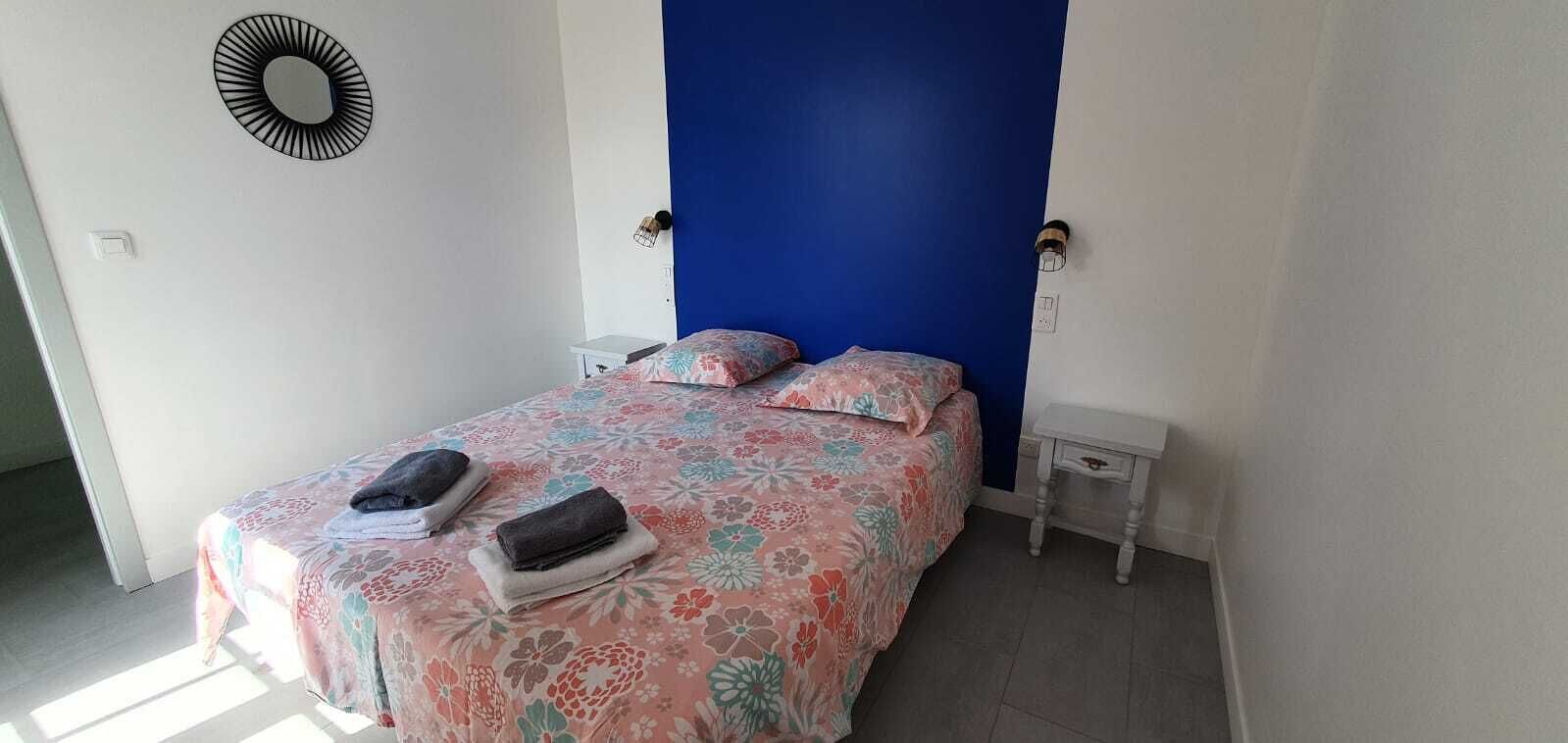 A bedroom with a bed, two nightstands, a blue accent wall, and a circular wall decoration.