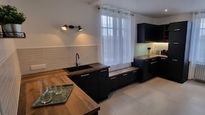 Una cocina moderna con armarios negros, encimera de madera y horno empotrado.