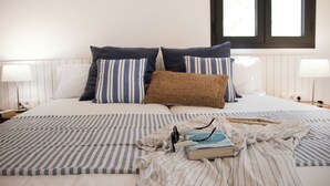 Een net opgemaakt bed met gestreepte lakens, een boek en een bril erop.