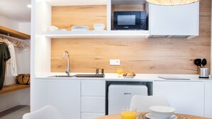 Een moderne keuken met witte kastjes, een magnetron en een spoelbak. Er staat een ontbijtje klaar met croissants en sinaasappelsap op het aanrecht.