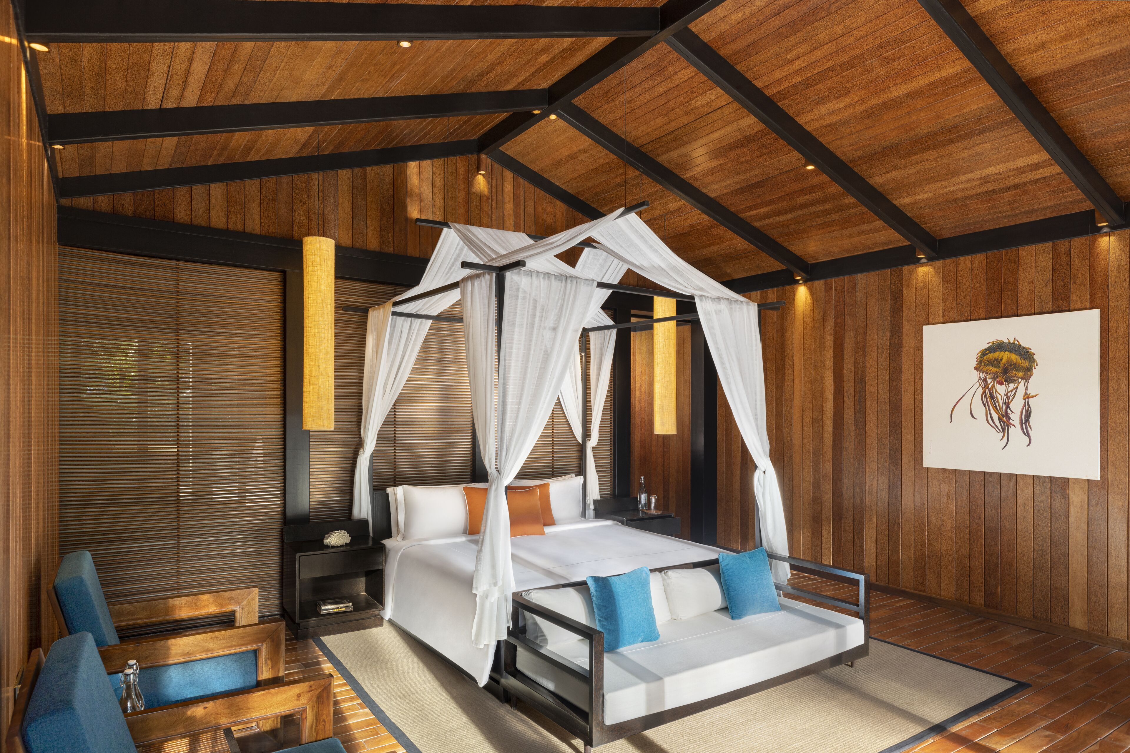 A bedroom with a canopy bed, a sofa, and a nightstand.