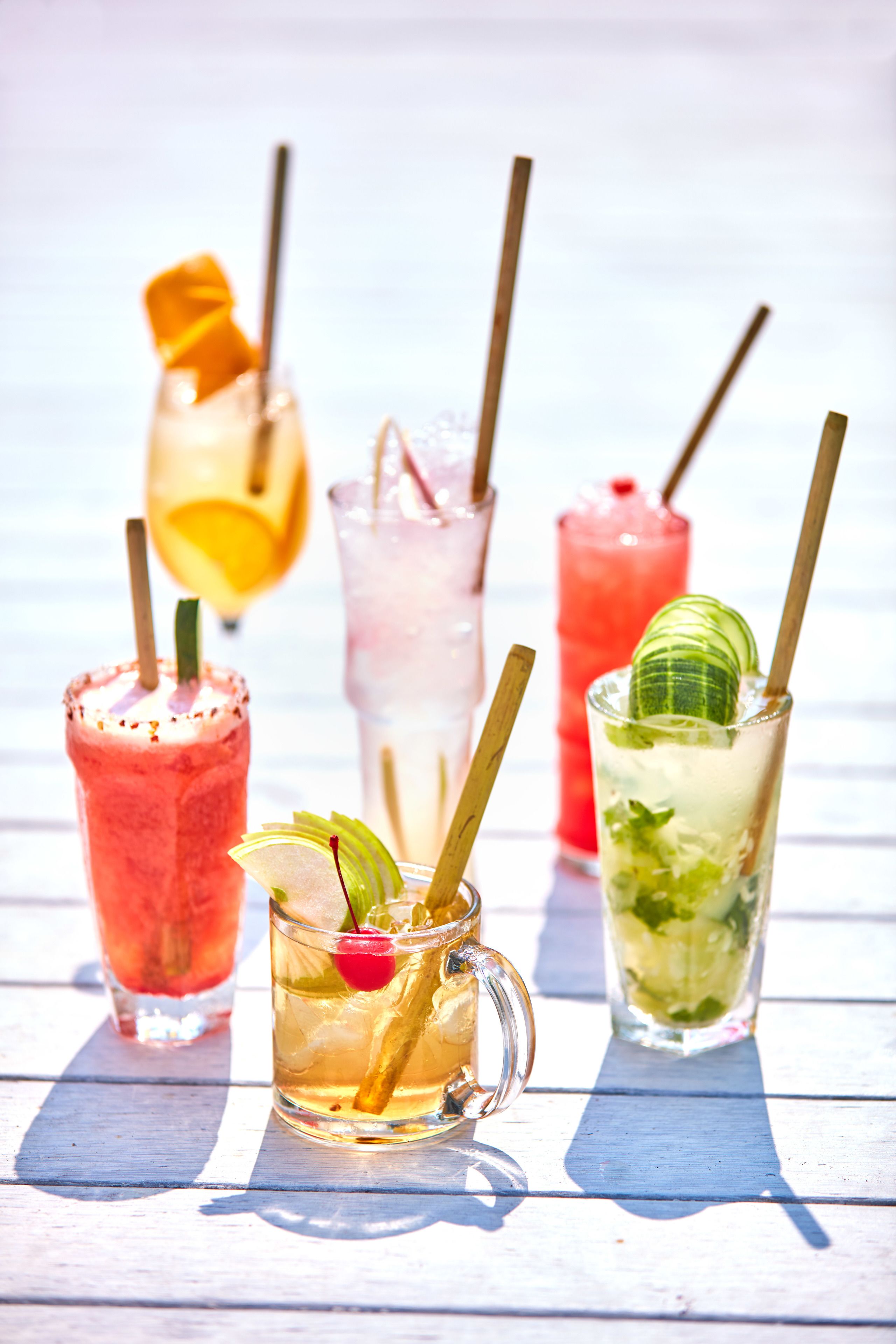 A variety of colorful cocktails on a wooden table.
