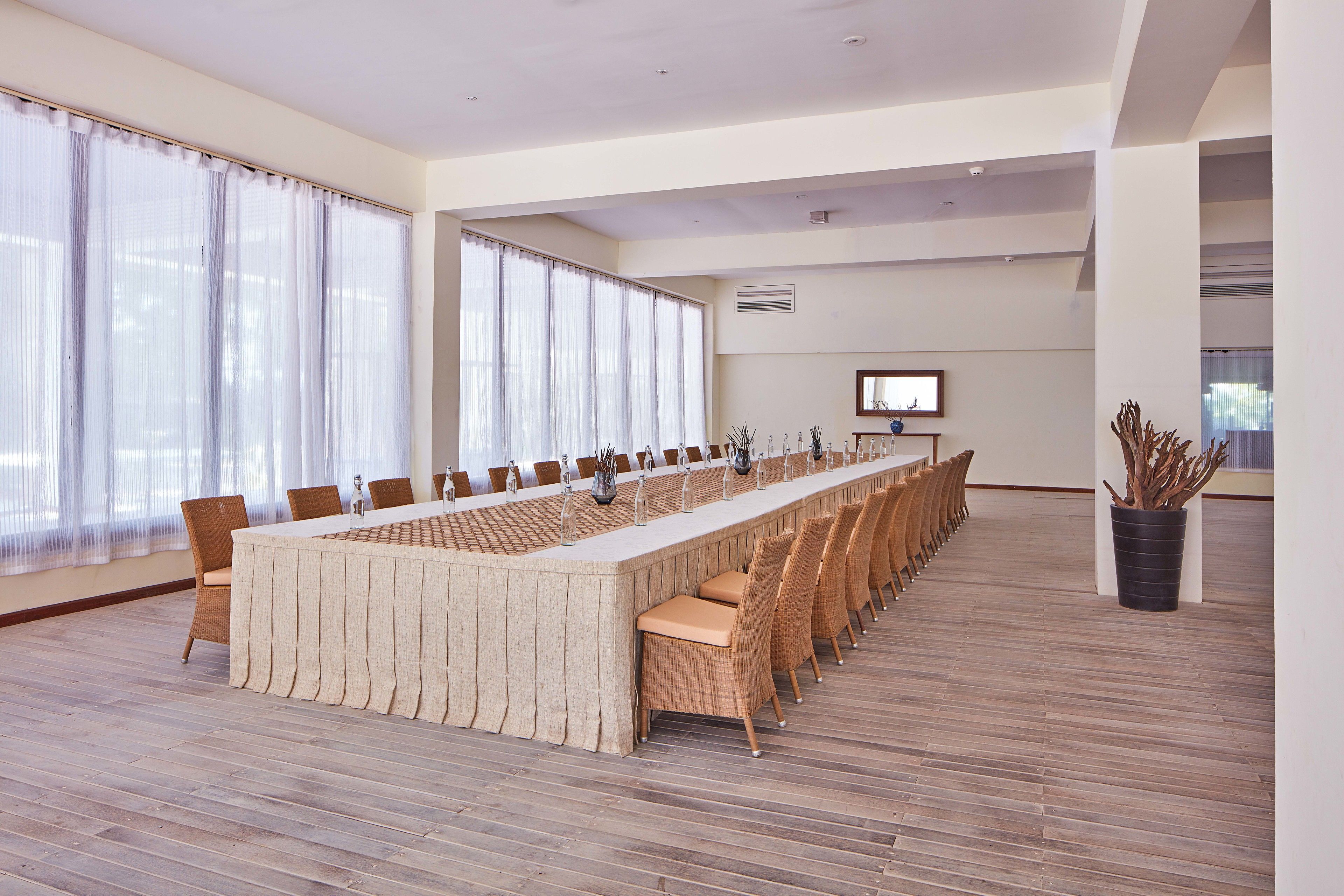 Un salón de conferencias con una larga mesa, sillas y una pantalla de televisión.