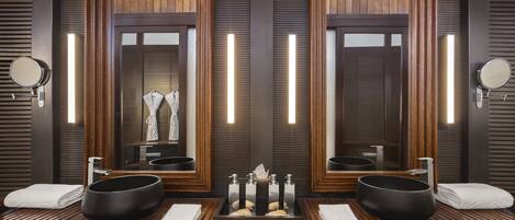 A modern bathroom with two large mirrors, wooden vanity, and black vessel sinks.
