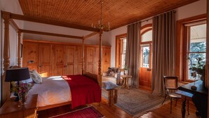 Un dormitorio amplio con una cama grande, un armario de madera y una araña.